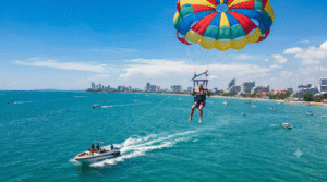 photograph of an adult tourist parasailing high above the turquoise waters of Pattaya,