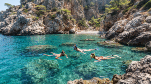 coastal adventure photograph of three adult friends snorkeling in a secluded rocky cove in Rhodes,