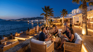 night scene in Mykonos, Greece, sophisticated open-air beach club overlooking the Aegean Sea, stylish travellers enjoying cocktails and music, elegant ambient lighting, palm trees moving gently in the night