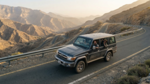 professional road-trip photograph on a mountain road in Ras Al Khaimah, UAE, real SUV travelling along a winding road through the Hajar Mountains,