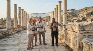 travel photograph of a small group of adult travellers exploring Hierapolis Ancient City near Pamukkale, Turkey, local guide explaining Roman ruins and carved stone details,