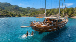 luxury sailing experience near Bodrum, Turkey, adult travellers relaxing on the deck of a traditional wooden Turkish gulet sailing through turquoise Aegean water, ru