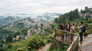 photograph of Shillong, Meghalaya, featuring rolling green hills, a scenic mountain viewpoint, lush vegetation and authentic hill-town surroundings