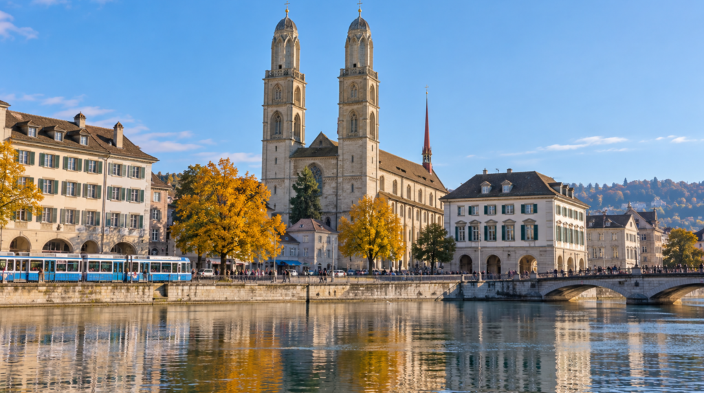 Grossmunster church in Zurich photographed from across the Limmat River on a clear autumn morning, twin towers reflected subtly in the river, historic waterfront buildings surrounding the church,