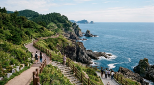 premium travel photograph of a scenic coastal walking trail in Busan, South Korea, dramatic rocky coastline, blue ocean