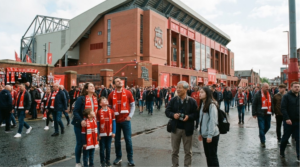 photograph of diverse random football tourists visiting Anfield in Liverpool, stadium architecture,