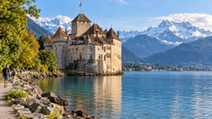 photograph of Chillon Castle near Montreux Switzerland, medieval stone castle standing beside the clear blue waters of Lake Geneva